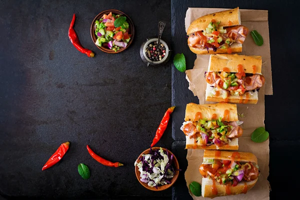 Hot dog - sandwich with Mexican salsa on dark background. T — Stock Photo, Image
