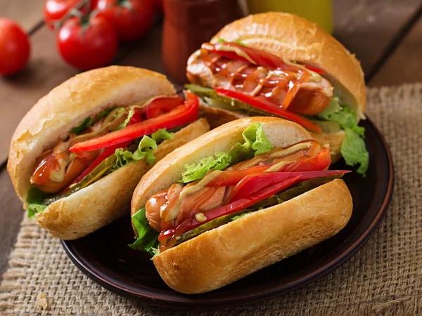 Hot dog - sandwich with pickles, paprika and lettuce on wooden background — Stock Photo, Image