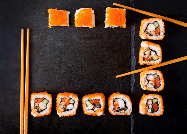 Traditionell japansk mat - sushi, rullar och ätpinnar för sushi på en mörk bakgrund. — Stockfoto