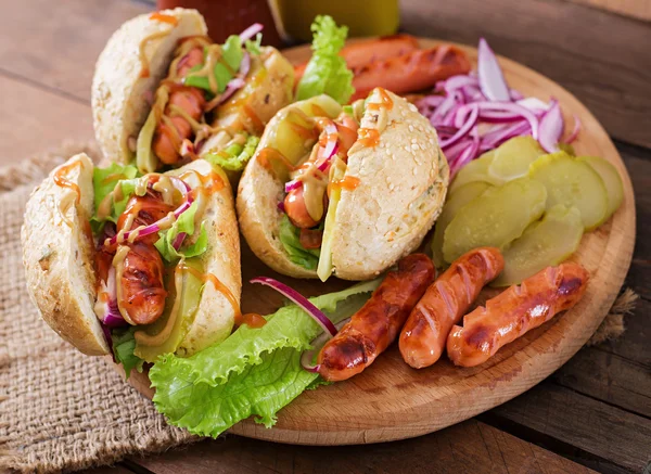 Hot dog - sandwich with pickles, red onions and lettuce on wooden background — Stock Photo, Image