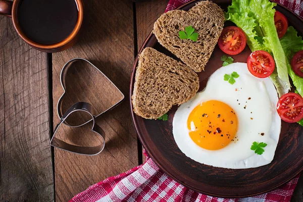 El desayuno el Día de San Valentín - los huevos fritos y el pan en forma del corazón — Foto de Stock