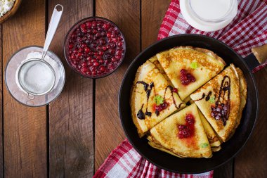 Golden pancakes with cranberry jam and honey in a rustic style