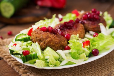 uicy meat cutlets with cranberry sauce and salad on a wooden table in a rustic style.