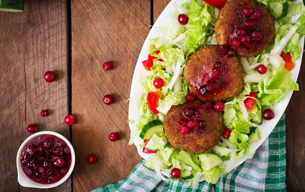 Uicy meat cutlets with cranberry sauce and salad on a wooden table in a rustic style. — Stockfoto