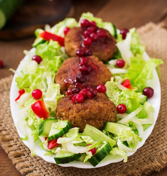 Uicy meat cutlets with cranberry sauce and salad on a wooden table in a rustic style. — Stock Photo, Image