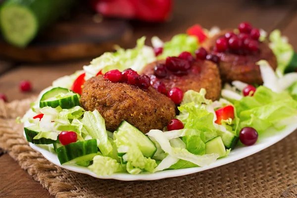 Uicy meat cutlets with cranberry sauce and salad on a wooden table in a rustic style. — Stock Fotó