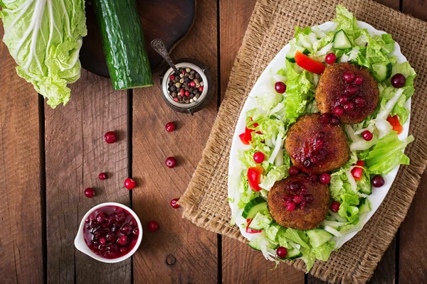 Bucăți de carne înghețată cu sos de afine și salată pe o masă de lemn într-un stil rustic . — Fotografie, imagine de stoc