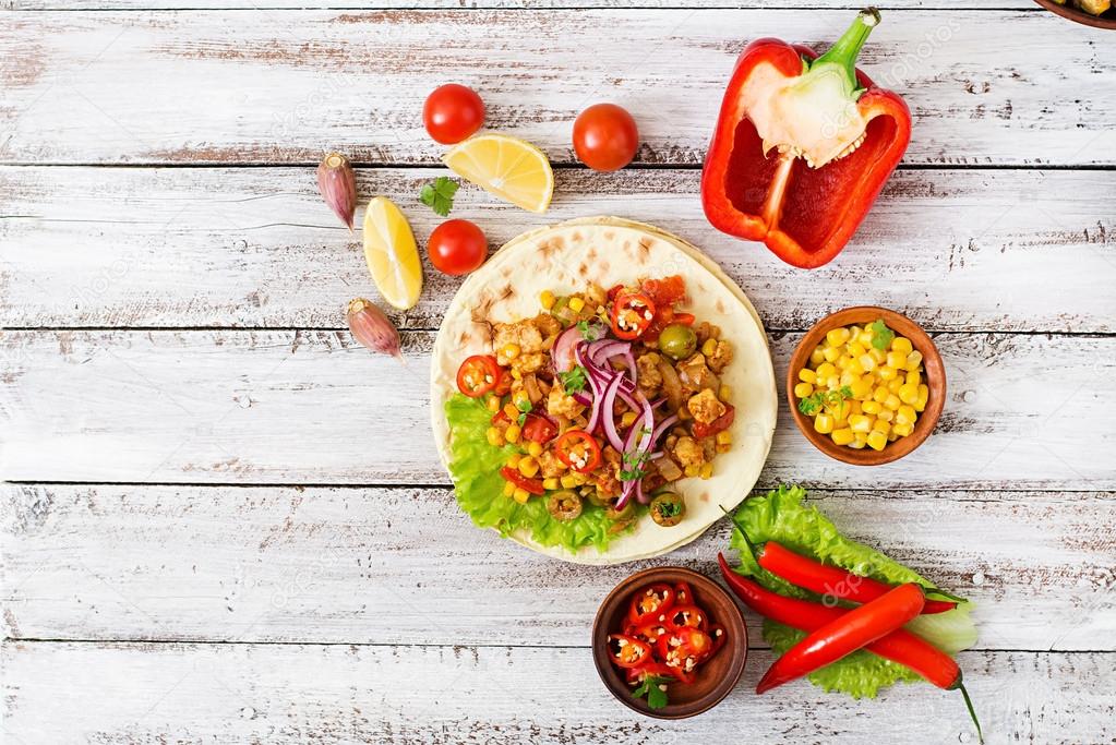 Mexican tacos with meat, corn and olives on wooden background