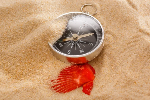 Black compass and sea shell in sand — Stock Photo, Image