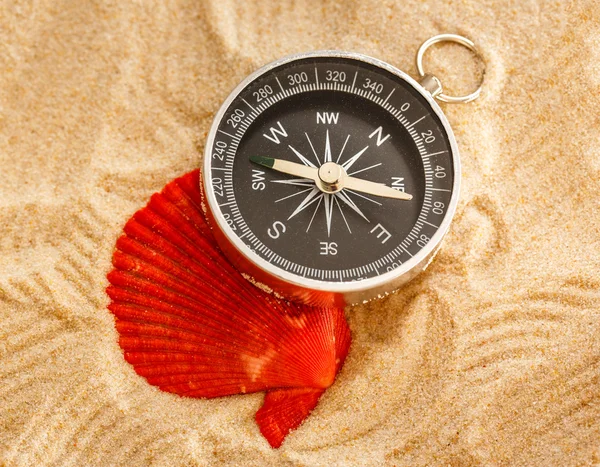 Svart kompass och sea shell i sand — Stockfoto