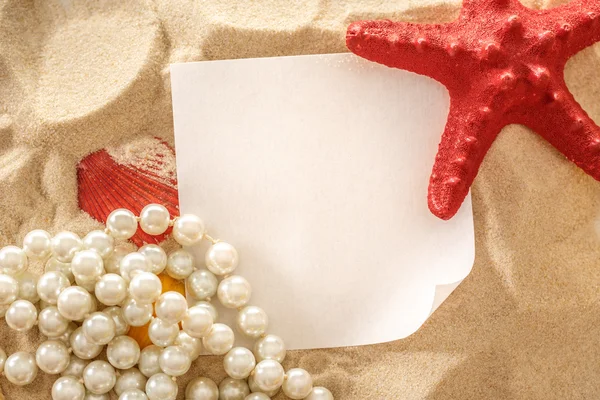 Pearl, seashells and paper on sand — Stock Photo, Image