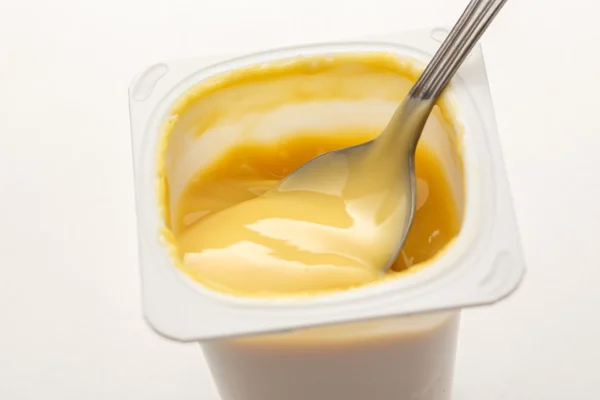 Yogurt aperto in pentola con cucchiaio di metallo — Foto Stock