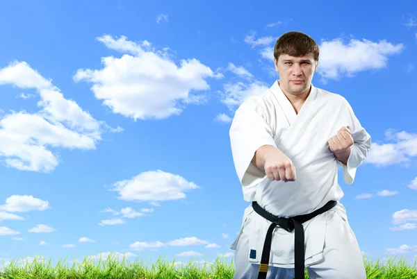 Karate-Meister im Kimono bei blauem Himmel — Stockfoto