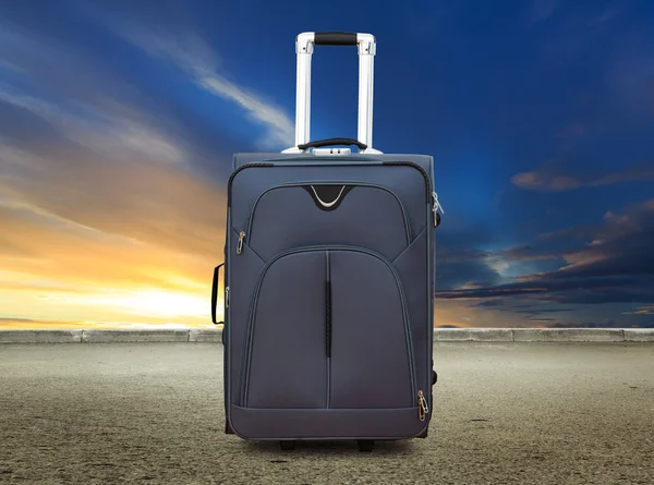 Suitcase at sunset sky and road — Stock Photo, Image