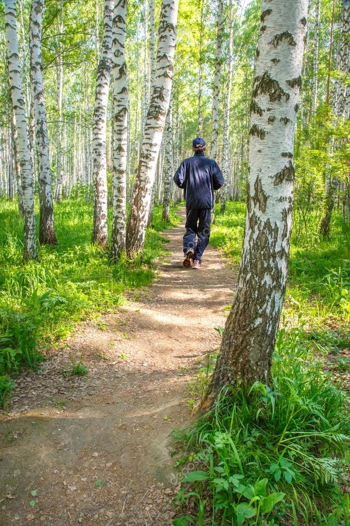 Um homem correndo em um caminho na floresta