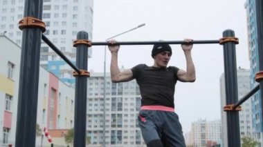 Kaslı adam spor sahasında antrenman yapıyor.