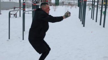 Adam kışın spor sahasında antrenman yapıyor.