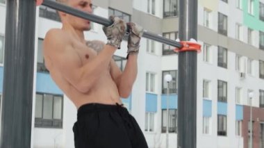 Kışın spor sahasında üstsüz antrenman yapan kaslı bir adam.