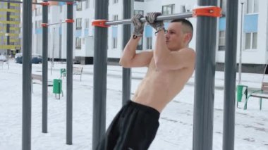 Kışın spor sahasında üstsüz antrenman yapan kaslı bir adam.