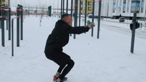 Hombre entrenando al aire libre en el campo de deportes en invierno — Vídeos de Stock