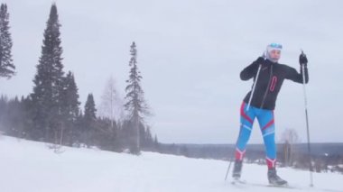 Genç bir kadın ormanda kayak yapıyor.