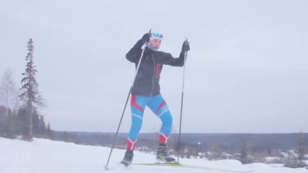 Mujer joven esquiando en un sendero forestal — Vídeo de stock