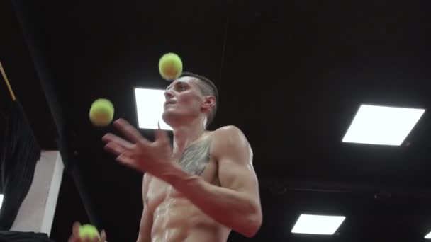 Muscular man juggling with three balls — Stock Video