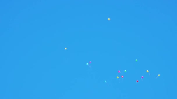 Барвисті кульки, що летять у блакитному небі — стокове відео