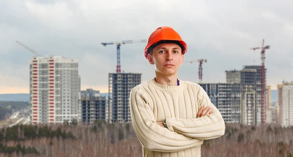 Workman i röd hjälm på bakgrund av byggnader — Stockfoto