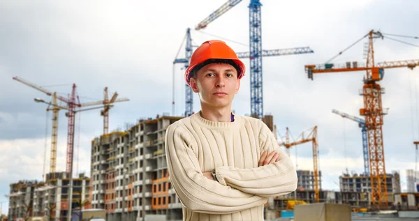 Workman i röd hjälm på bakgrund av byggnader — Stockfoto