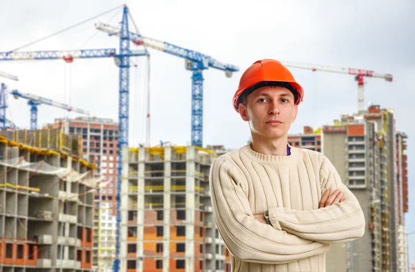 Workman i röd hjälm på bakgrund av byggnader — Stockfoto