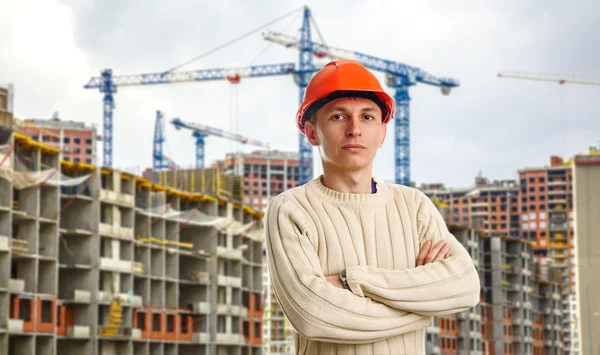 Workman i röd hjälm på bakgrund av byggnader — Stockfoto