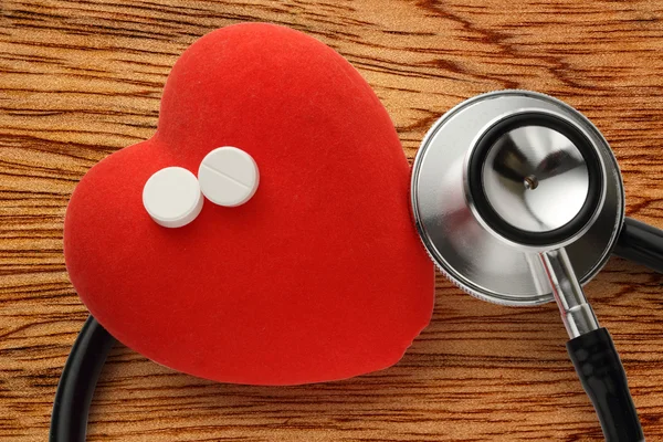 Красное сердце, стетоскоп и таблетки — стоковое фото