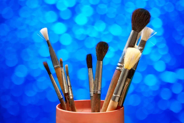 Paintbrushes in can on blue background — Stock Photo, Image