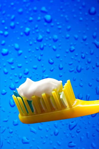 Cepillo de dientes y pasta de dientes sobre fondo azul — Foto de Stock