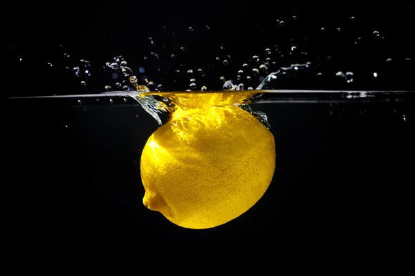 Limón amarillo en agua salpicada — Foto de Stock