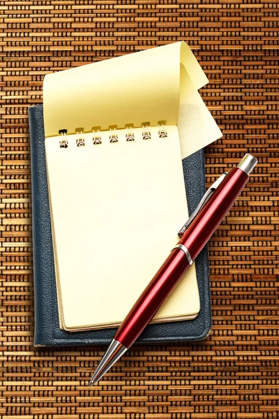 Bloc de notas en blanco amarillo con pluma roja — Foto de Stock