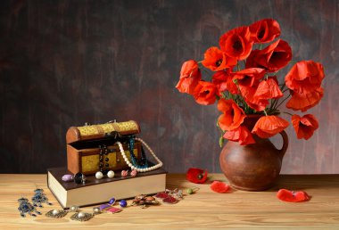 Takı, kitap ve haşhaş bir vazoda