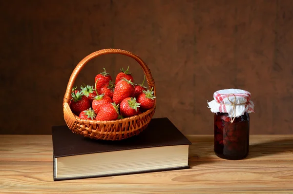 Fraises fraîches dans un panier en osier, livres et confitures — Photo