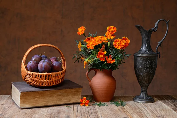 Fresh plums in a wicker basket and flowers — Stock Photo, Image