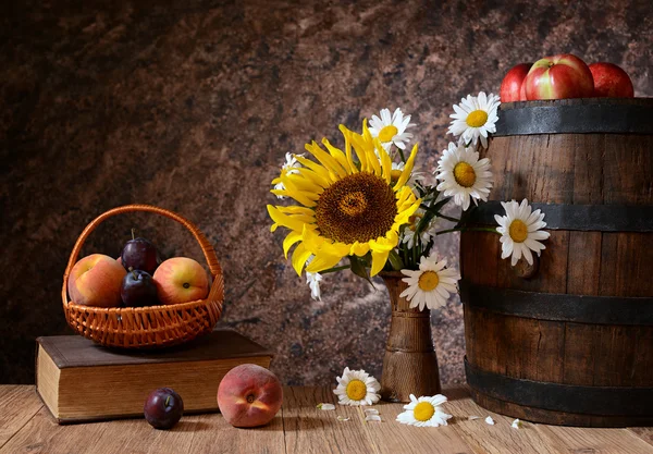 Daisy blommor i en vas med färska frukter i vicker korg — Stockfoto