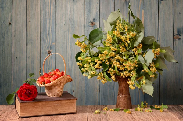 Linden flowers in a ceramic vase and cherries — Stock Photo, Image