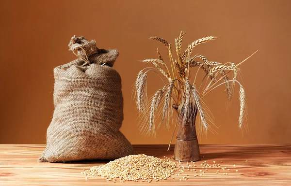 Grains of wheat, jute bag and ceramic vase — Stock Photo, Image