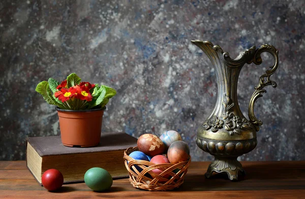 Huevos de Pascua en una cesta de mimbre y jarra de metal —  Fotos de Stock