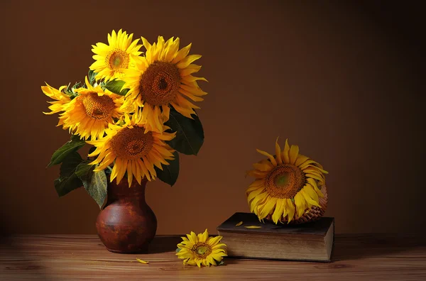 Girasol en un jarrón de cerámica, libros y canasta de mimbre —  Fotos de Stock