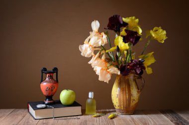 Sarı süsen, amphora, elma ve kitap