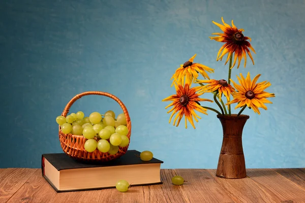 Druiven in rieten manden en bloemen in een vaas — Stockfoto