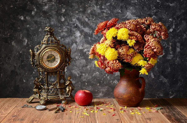 Klocka, äpplen och blommor i en keramik vas — Stockfoto