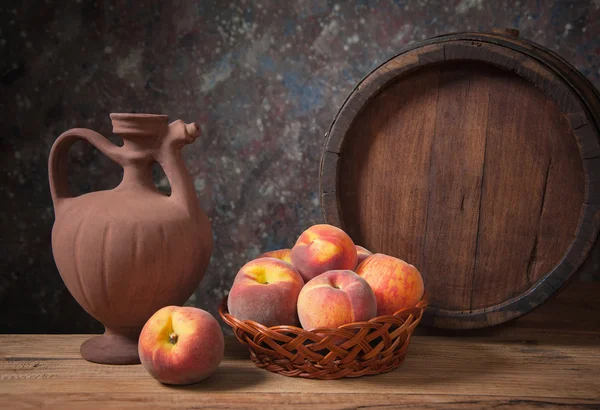 Fresh peaches in a wicker basket and her pitcher — Stock Photo, Image