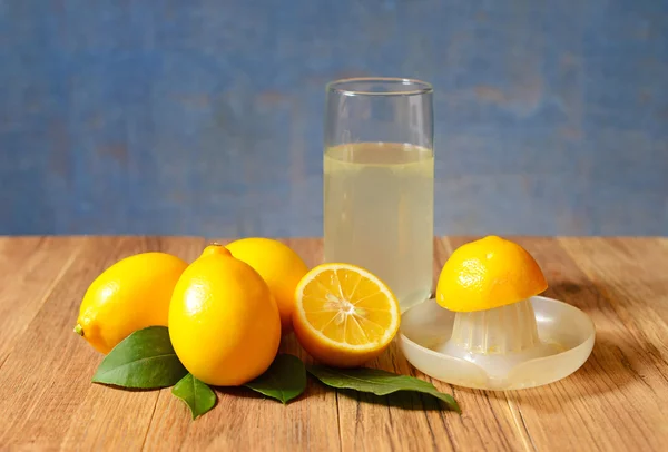 Jugo de limón recién exprimido en un vaso con limones maduros — Foto de Stock